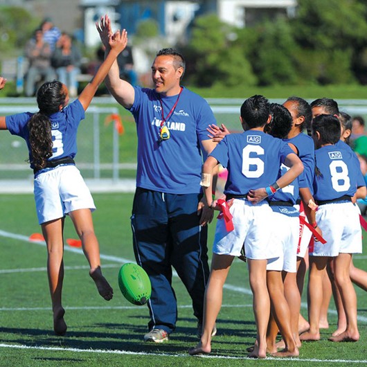 Coach hi-fives a girl after a practice rugby conversion image