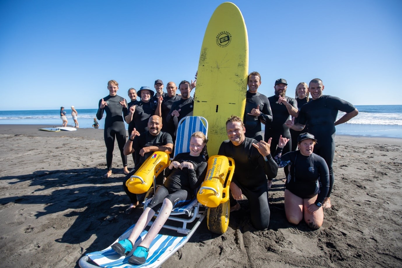 Group of people standing around a surfboard