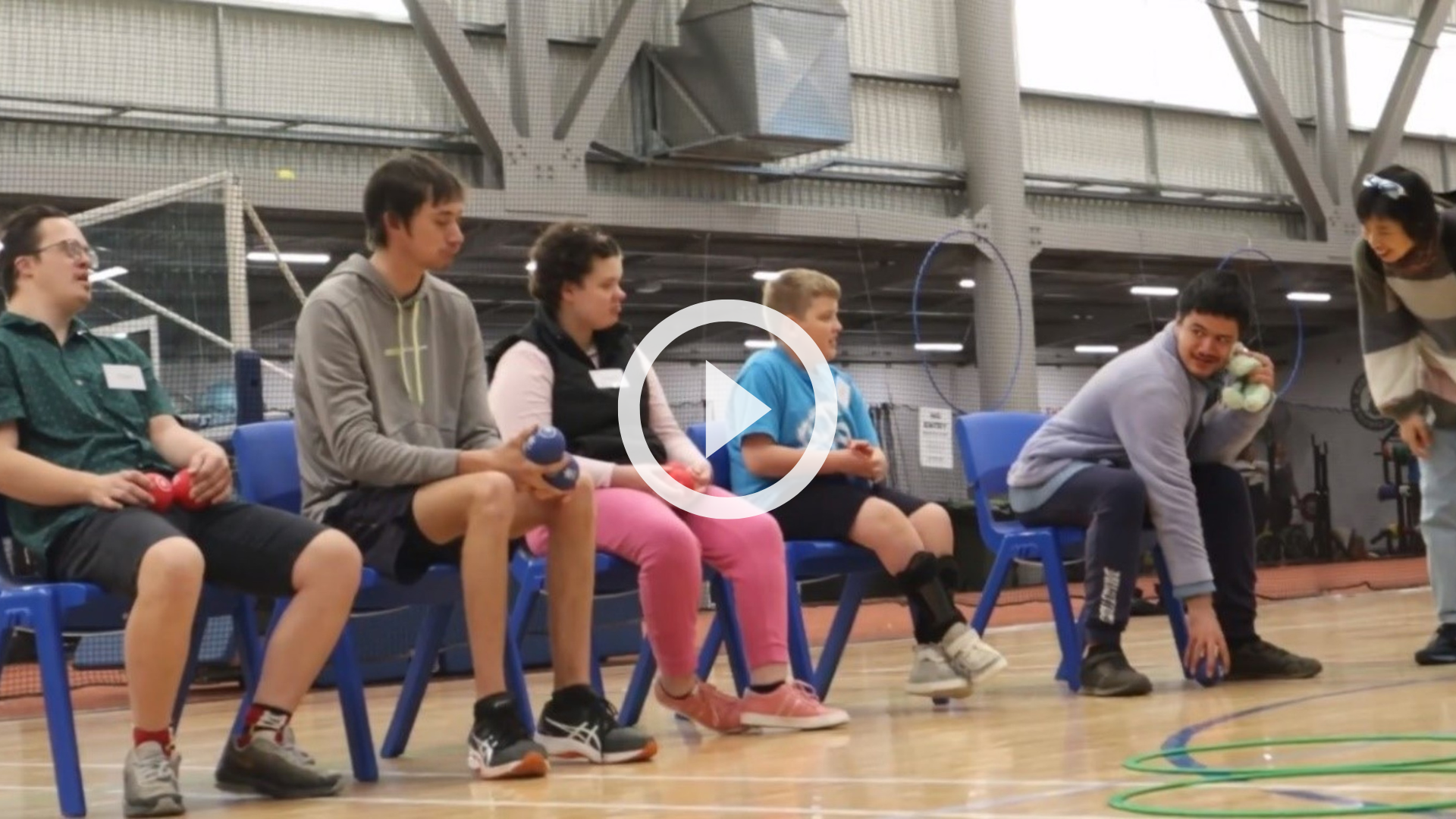 FIVE PEOPLE SITTING IN CHAIRS ON A BASKETBALL COURT