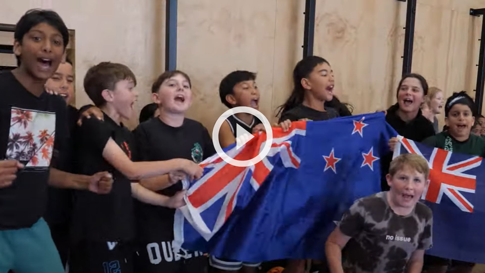 Tamariki holding the New Zealand flag chanting at a sports game